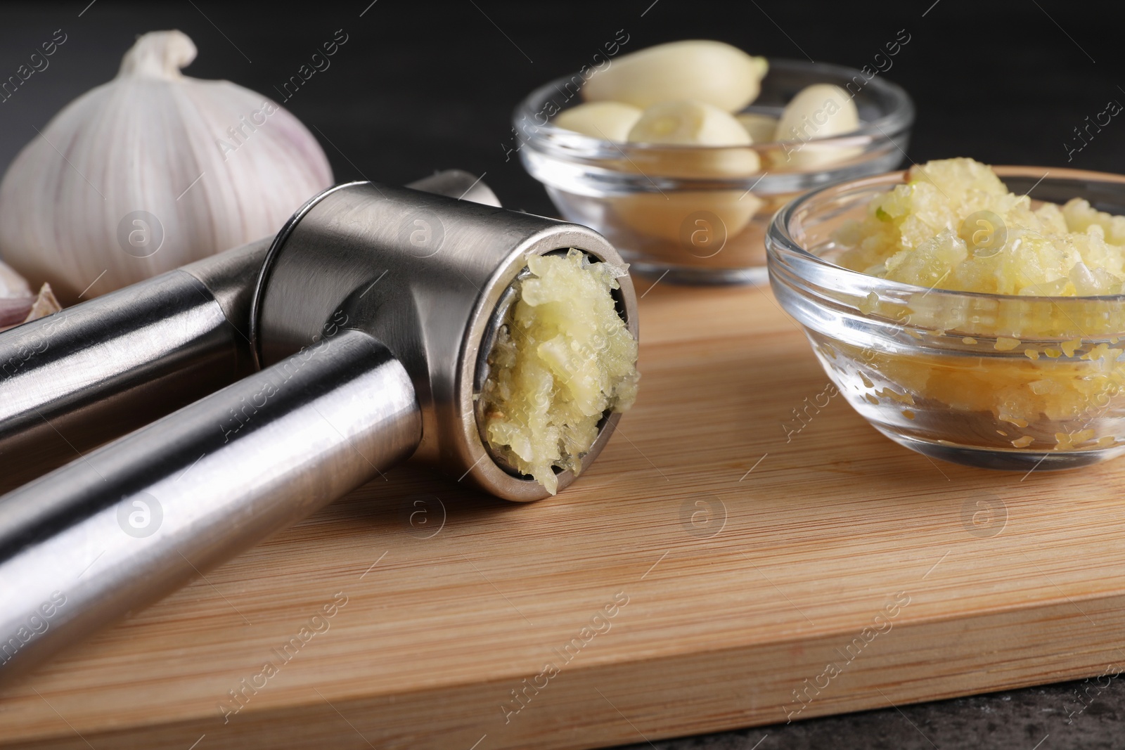 Photo of Garlic press and mince on wooden table, closeup