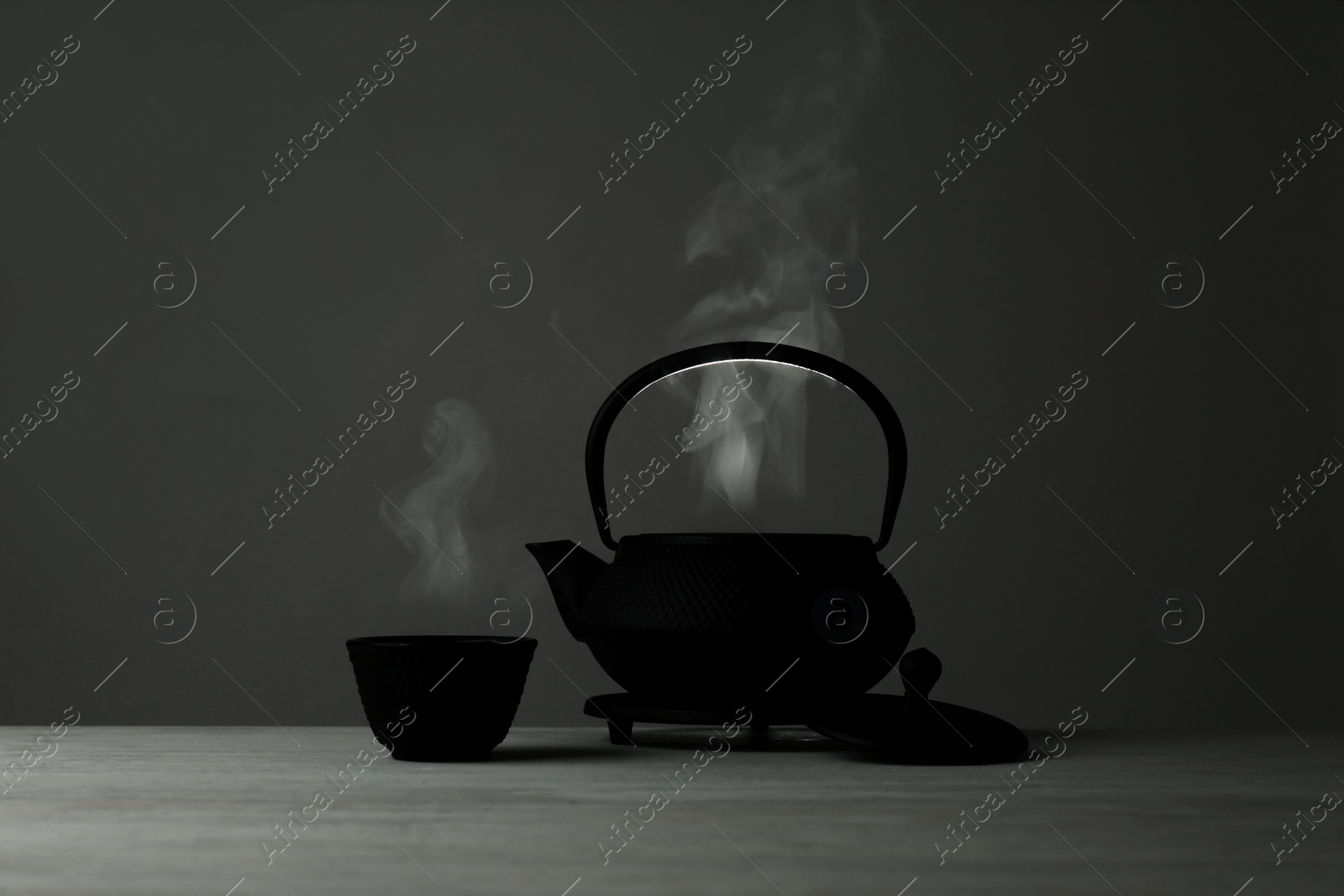 Photo of Oriental teapot and cup on table against grey background