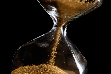 Hourglass with flowing sand on dark background, closeup. Time management