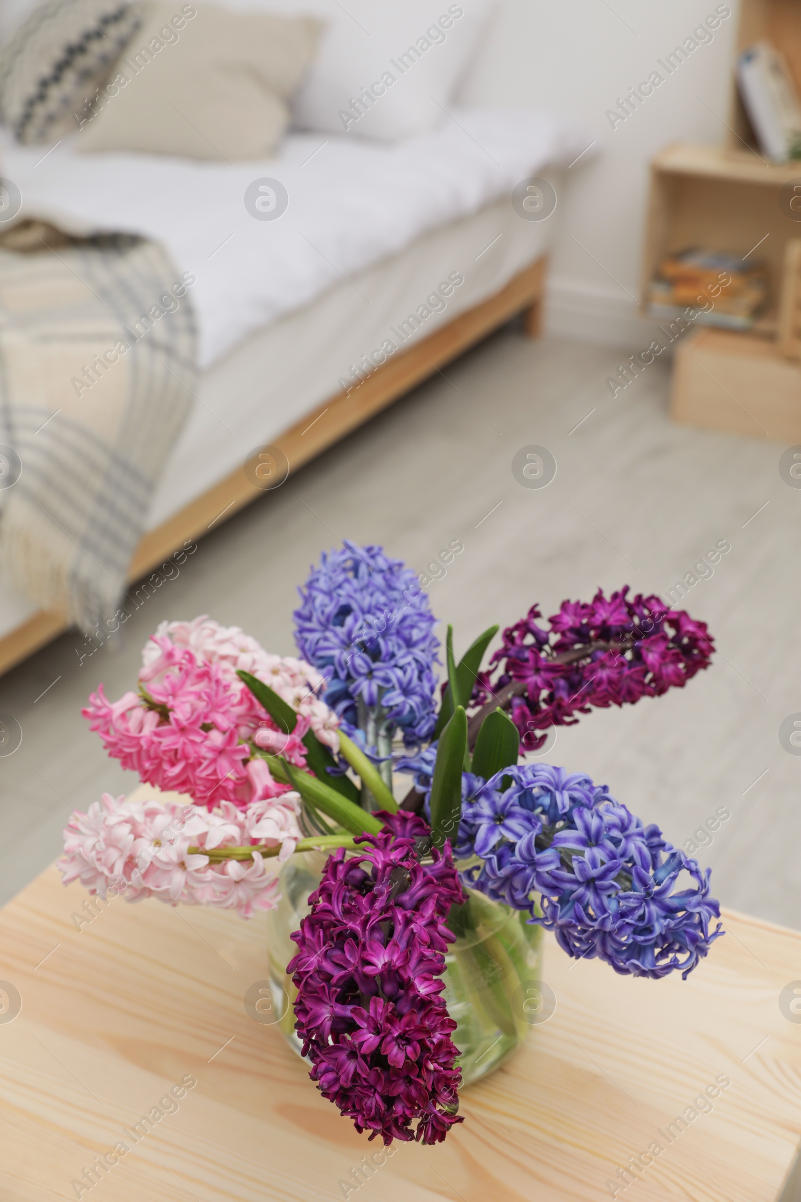 Photo of Beautiful hyacinths in glass vase on table indoors. Spring flowers