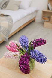 Photo of Beautiful hyacinths in glass vase on table indoors. Spring flowers