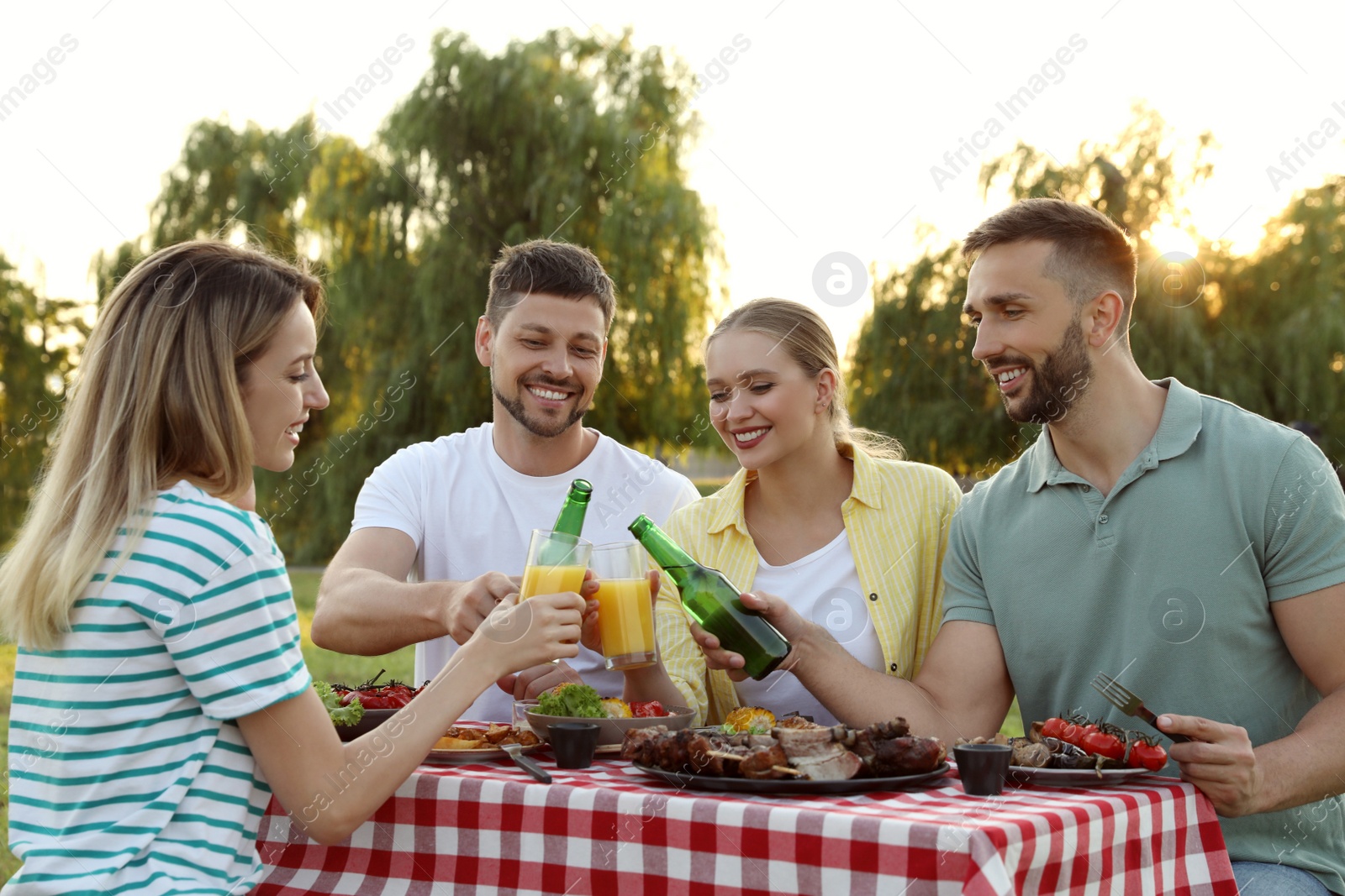 Photo of Happy friends with drinks and food at barbecue party in park