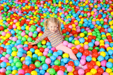 Photo of Cute child playing in ball pit indoors