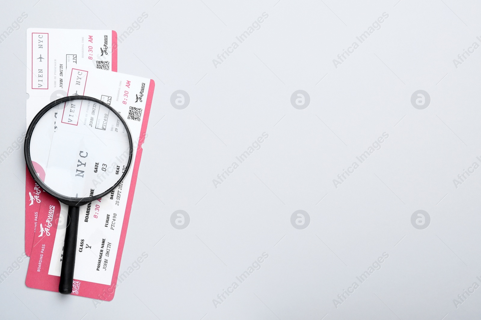 Photo of Tickets and magnifying glass on white background, flat lay with space for text. Travel agency concept