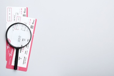 Photo of Tickets and magnifying glass on white background, flat lay with space for text. Travel agency concept
