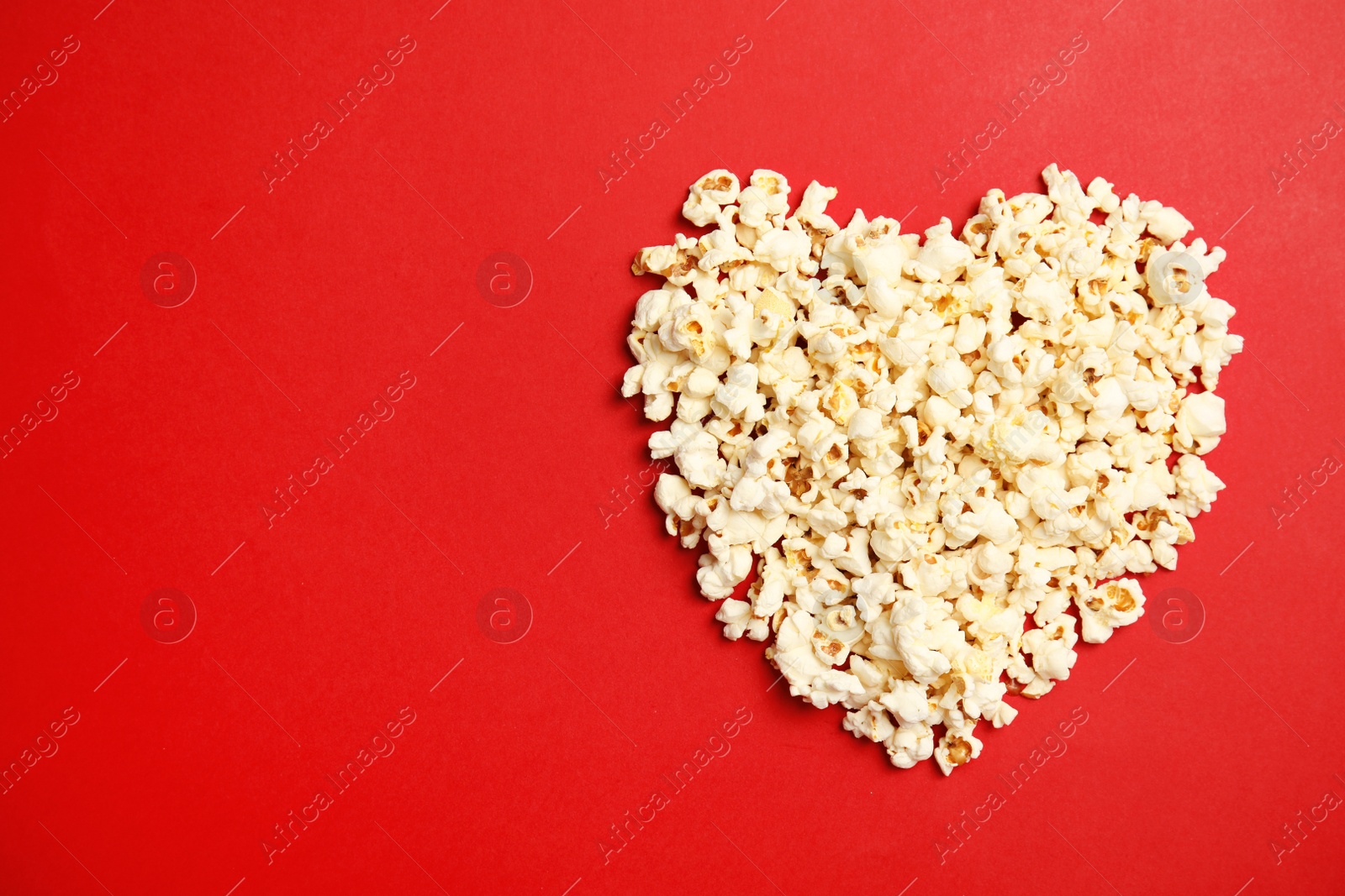 Photo of Tasty fresh popcorn on color background, top view