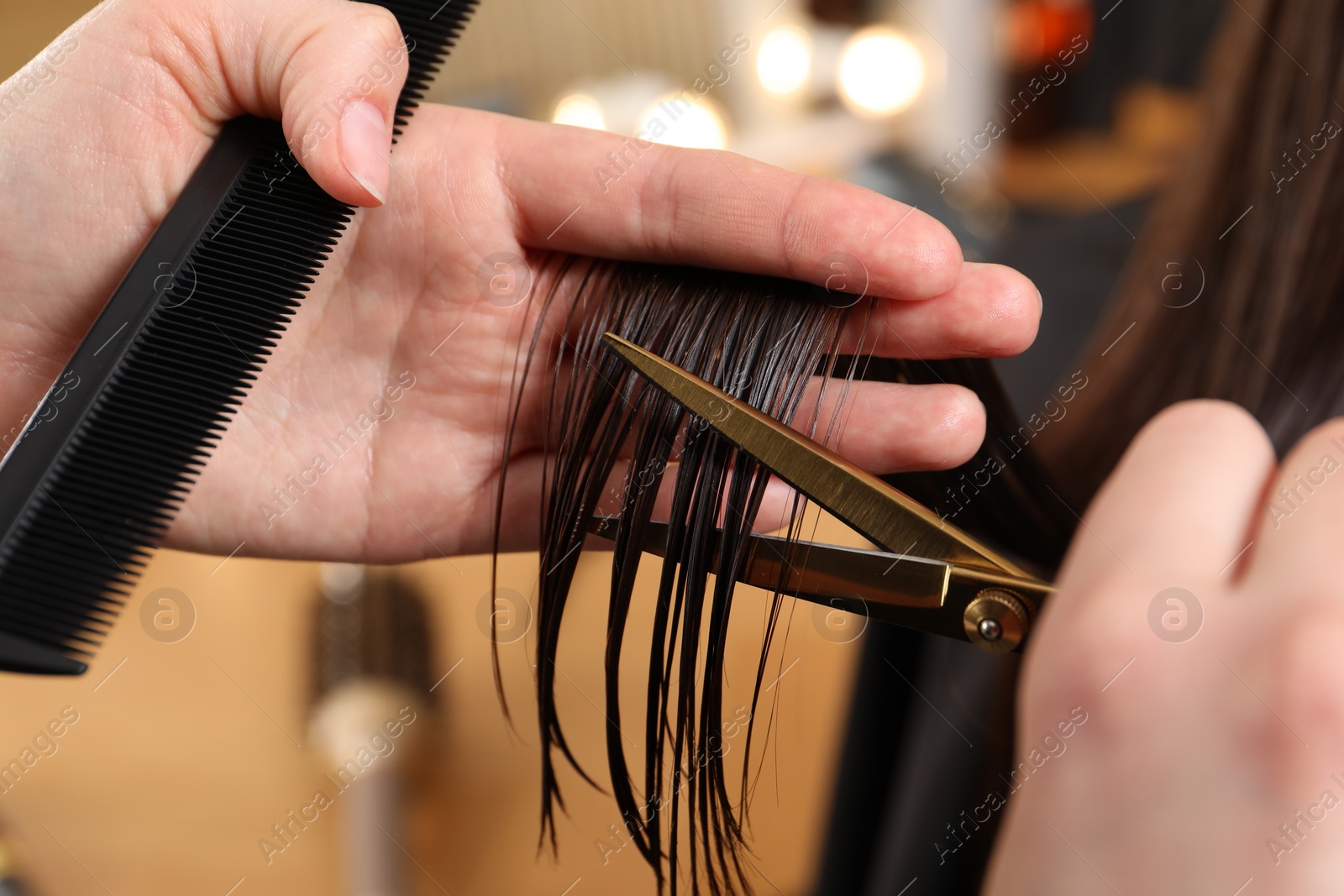 Photo of Hairdresser cutting client's hair with scissors in salon, closeup