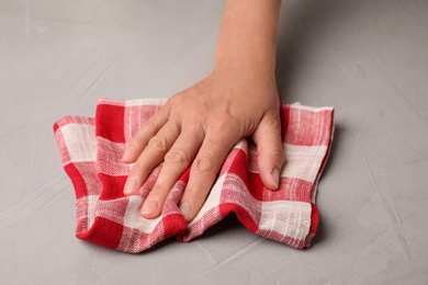 Photo of Woman wiping stone surface with kitchen towel, closeup