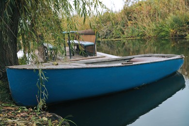 Light blue wooden boat on lake near pier