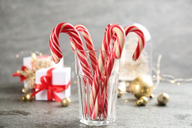 Photo of Christmas candy canes in glass on grey table