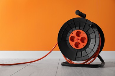 Extension cord reel on white floor indoors, space for text. Electrician's equipment