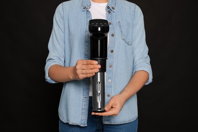 Woman holding sous vide cooker on black background, closeup