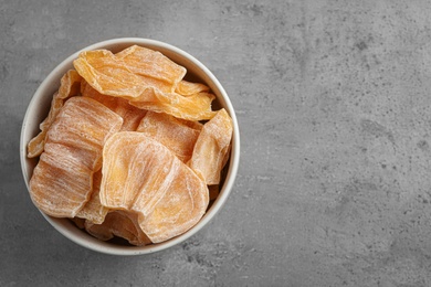 Delicious dried jackfruit slices in bowl on grey table, top view. Space for text