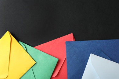 Photo of Colorful paper envelopes on black background, flat lay