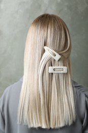 Photo of Young woman with beautiful hair clips on grey background, back view