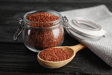 Spoon and jar with red quinoa on black wooden table