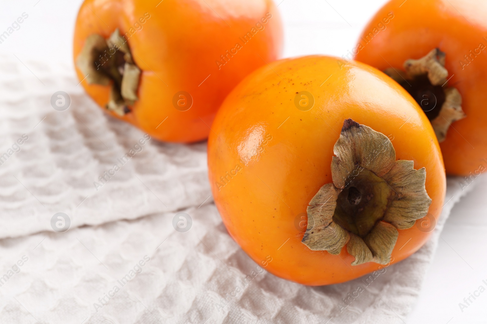 Photo of Delicious ripe persimmons on white table, closeup