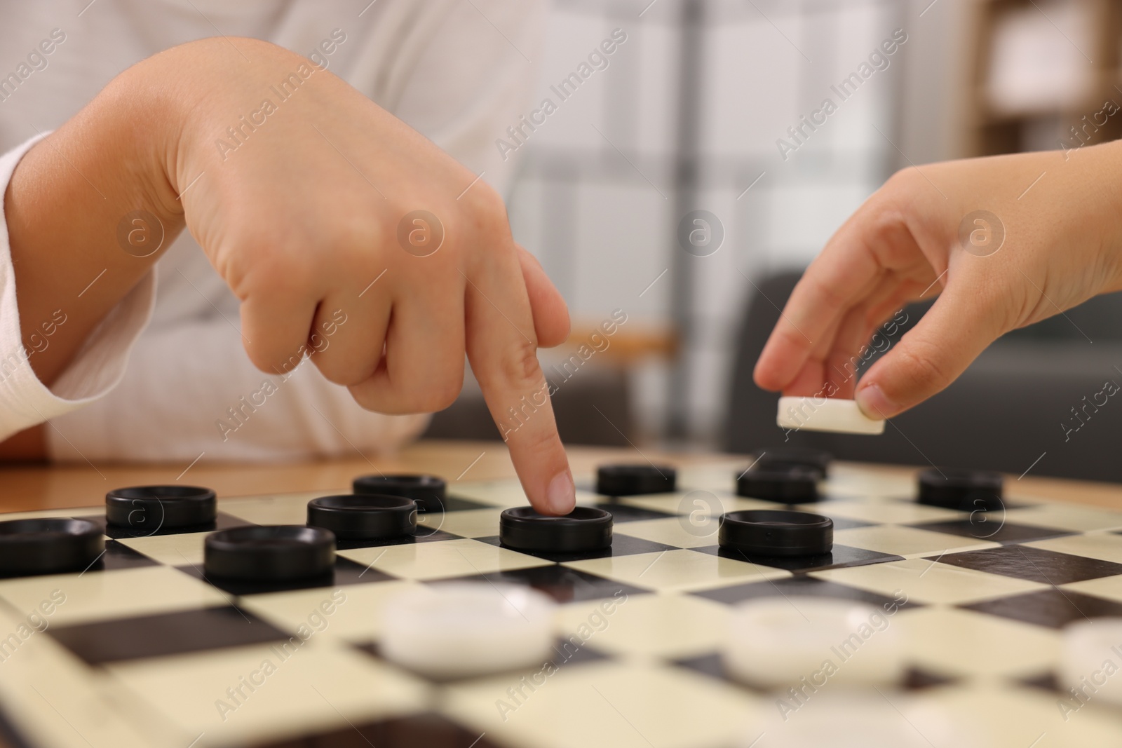 Photo of Children playing checkers at table indoors, closeup