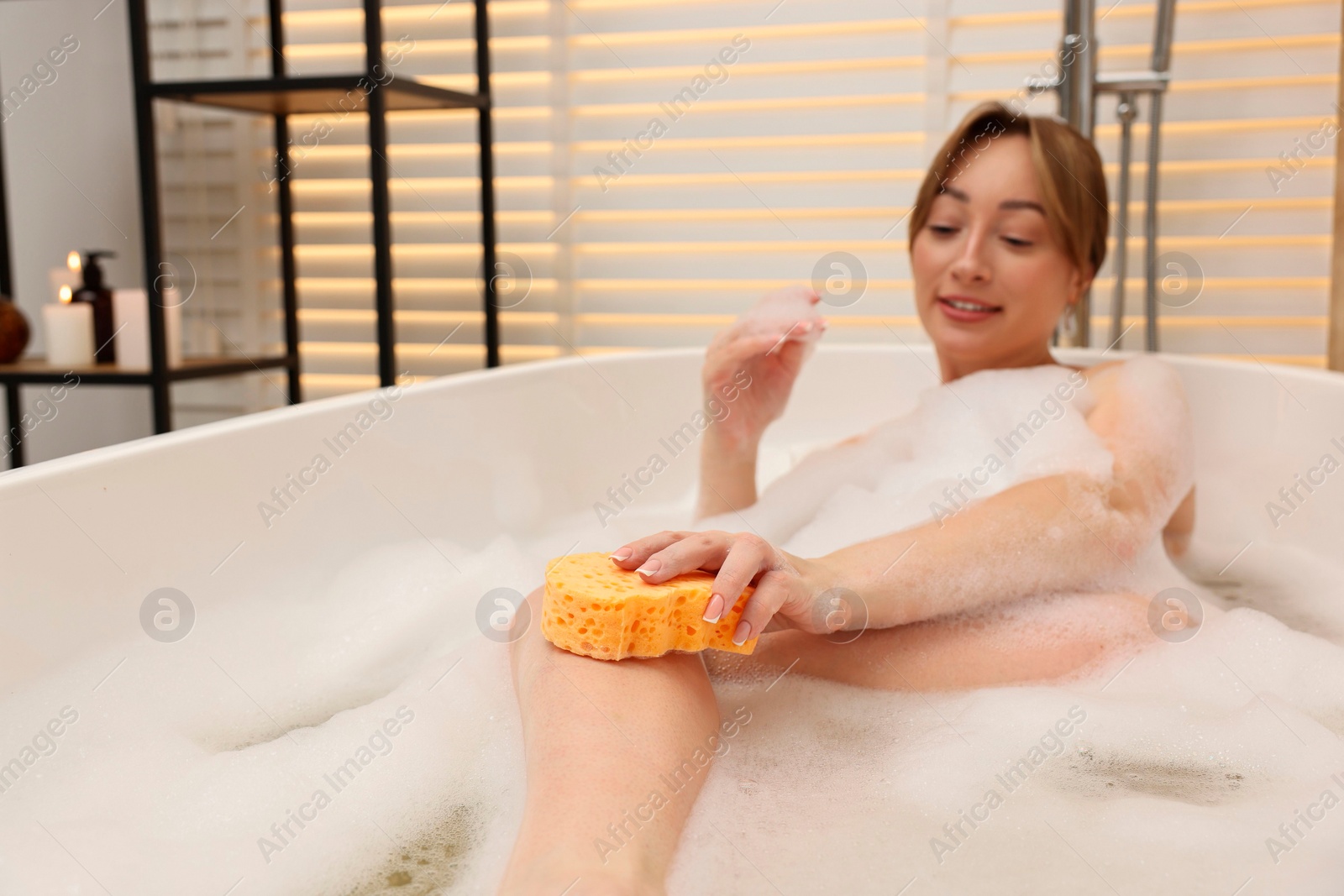 Photo of Happy woman taking bath with foam in tub indoors, selective focus