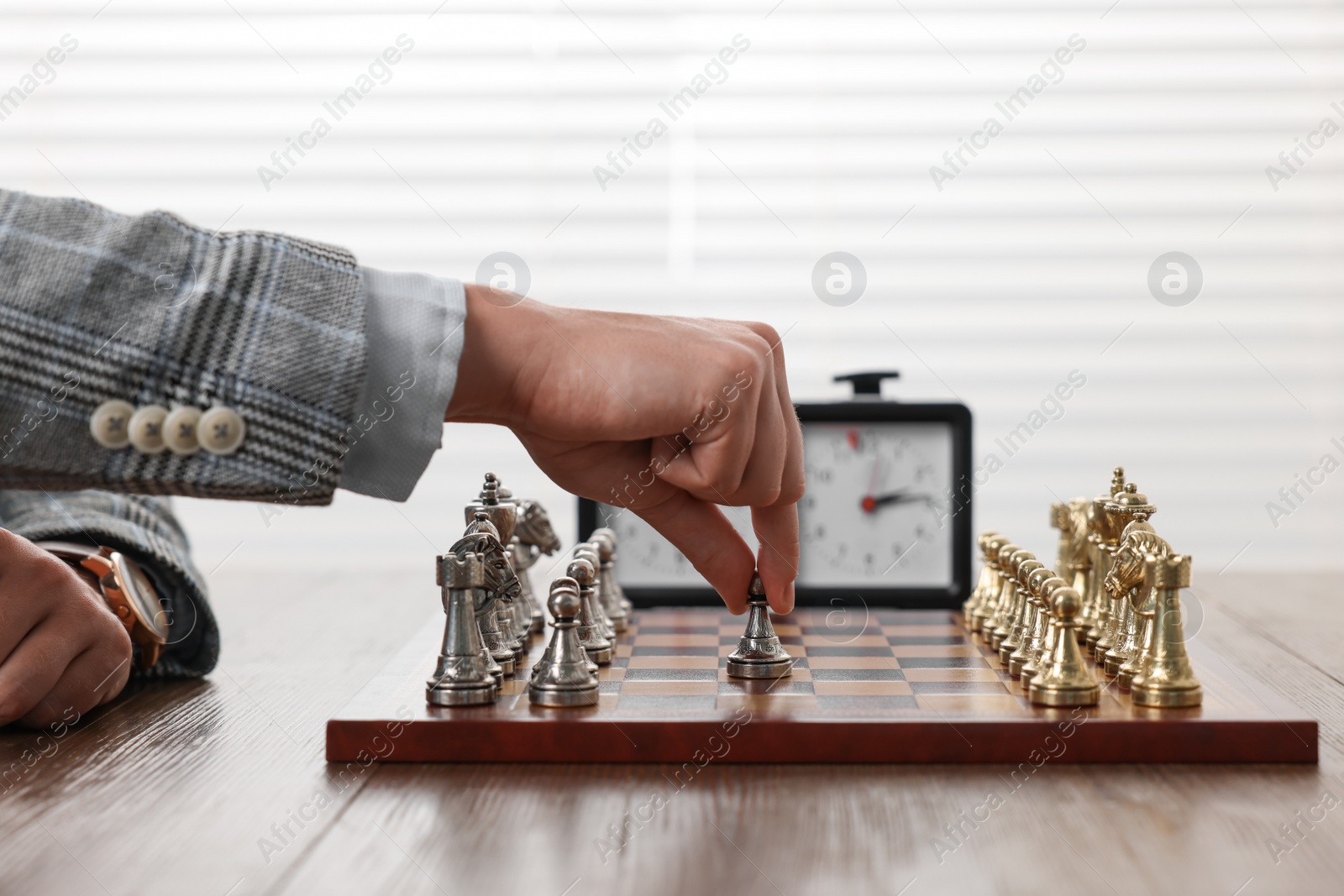 Photo of Man playing chess during tournament at table indoors, closeup