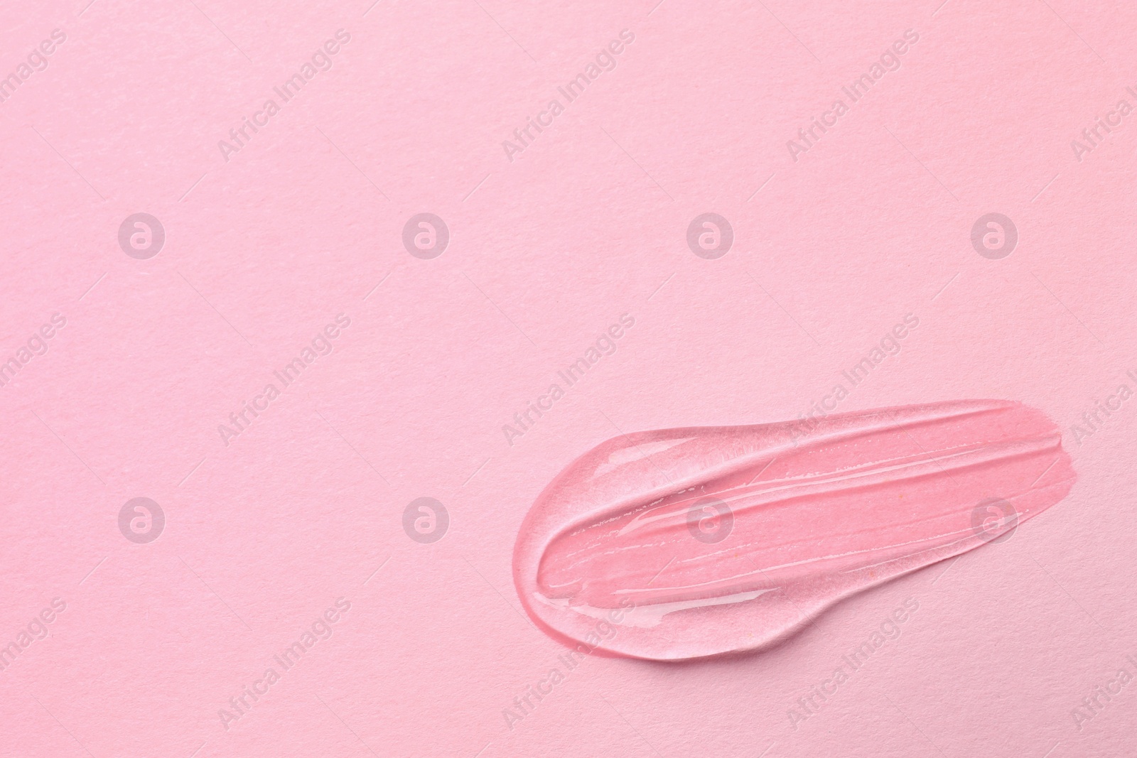 Photo of Sample of transparent gel on pink background, top view. Space for text