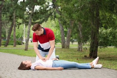 Passerby performing CPR on woman with heart attack outdoors