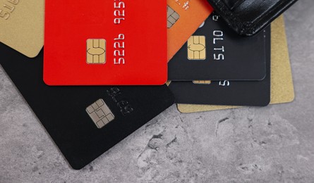 Photo of Pile of different credit cards on grey table, top view