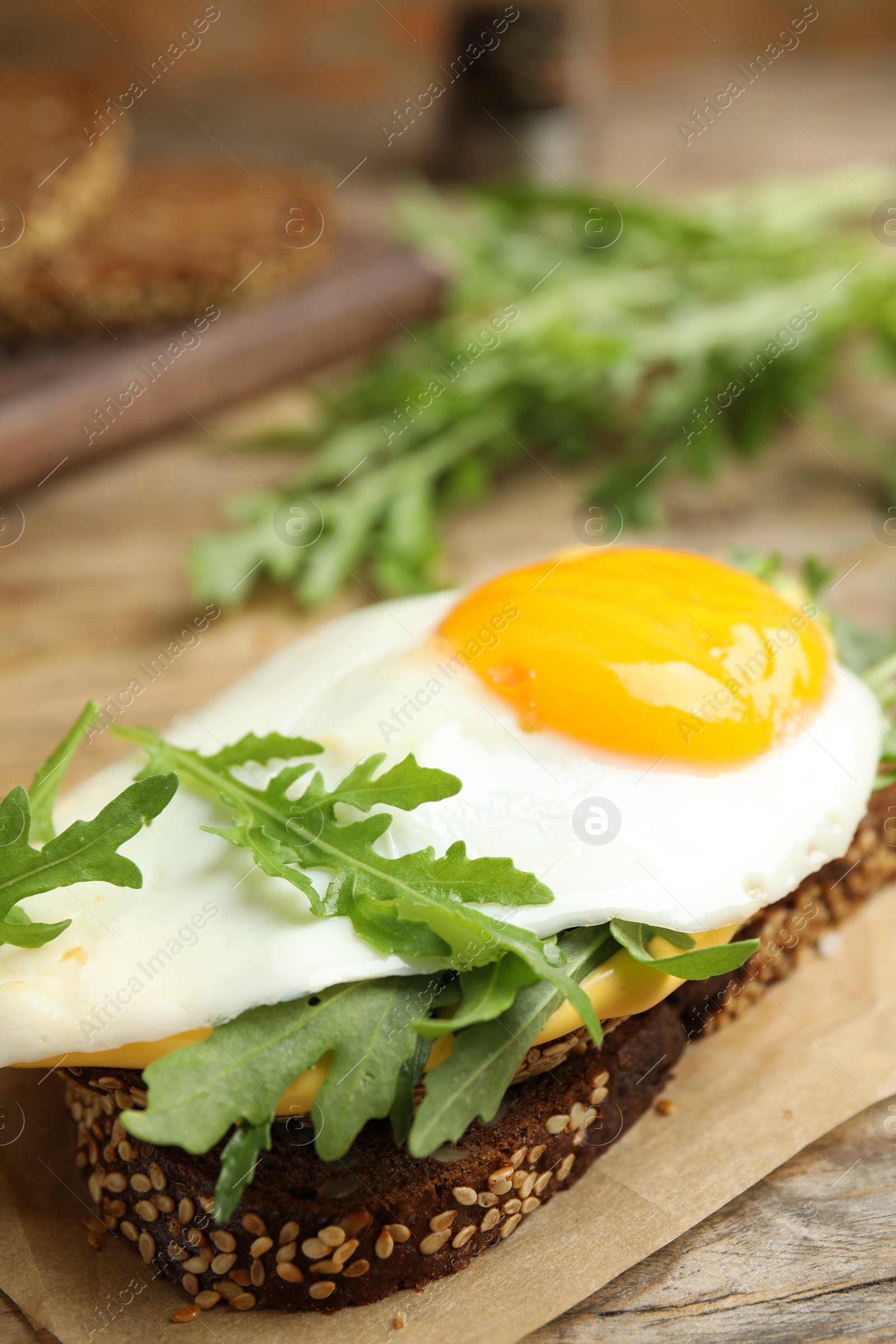 Photo of Delicious sandwich with arugula and egg on wooden table, closeup