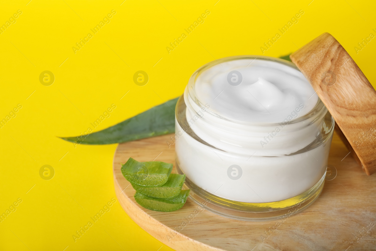 Photo of Jar of body cream with aloe on yellow background, closeup