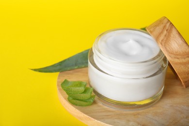 Jar of body cream with aloe on yellow background, closeup