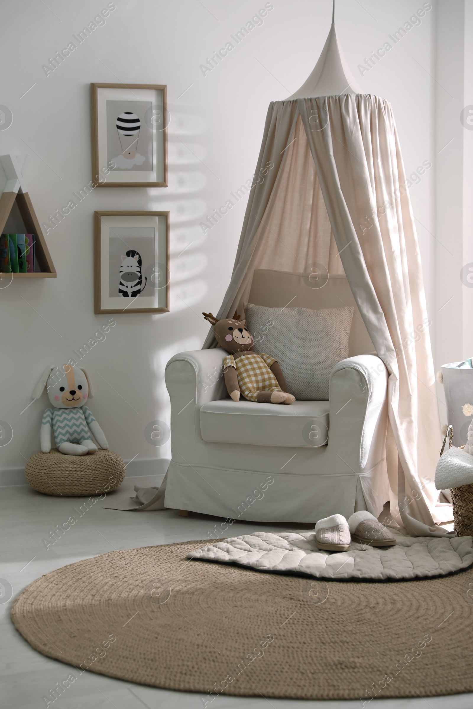 Photo of Stylish baby room interior with toys and comfortable armchair