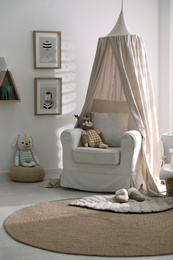 Stylish baby room interior with toys and comfortable armchair
