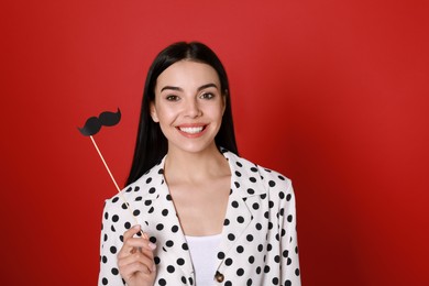 Happy woman with fake mustache on red background