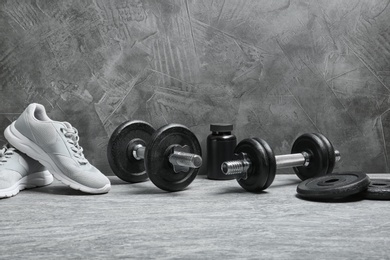 Photo of Composition with dumbbells and fitness accessories on floor. Space for text