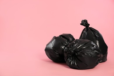 Photo of Trash bags full of garbage on pink background. Space for text