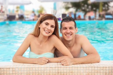 Photo of Happy couple resting in blue swimming pool outdoors