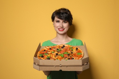 Photo of Attractive young woman with delicious pizza on color background