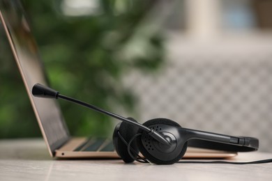 Photo of Headset and laptop on table indoors, closeup. Hotline concept