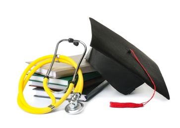 Stack of student textbooks, graduation hat and stethoscope on white background. Medical education