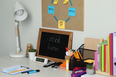 Photo of Business process planning and optimization. Workplace with lamp, small blackboard, colorful paper notes and other stationery on white wooden table