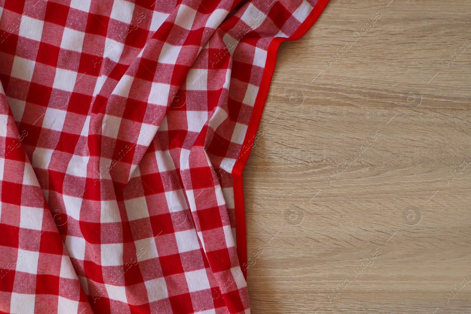 Photo of Checkered picnic cloth on wooden table, top view. Space for text