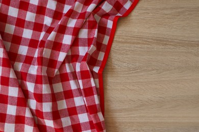 Checkered picnic cloth on wooden table, top view. Space for text