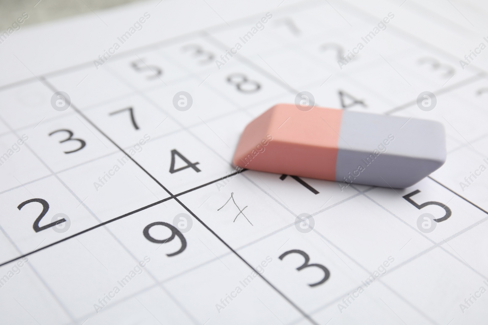 Photo of Sudoku puzzle grid and eraser, closeup view