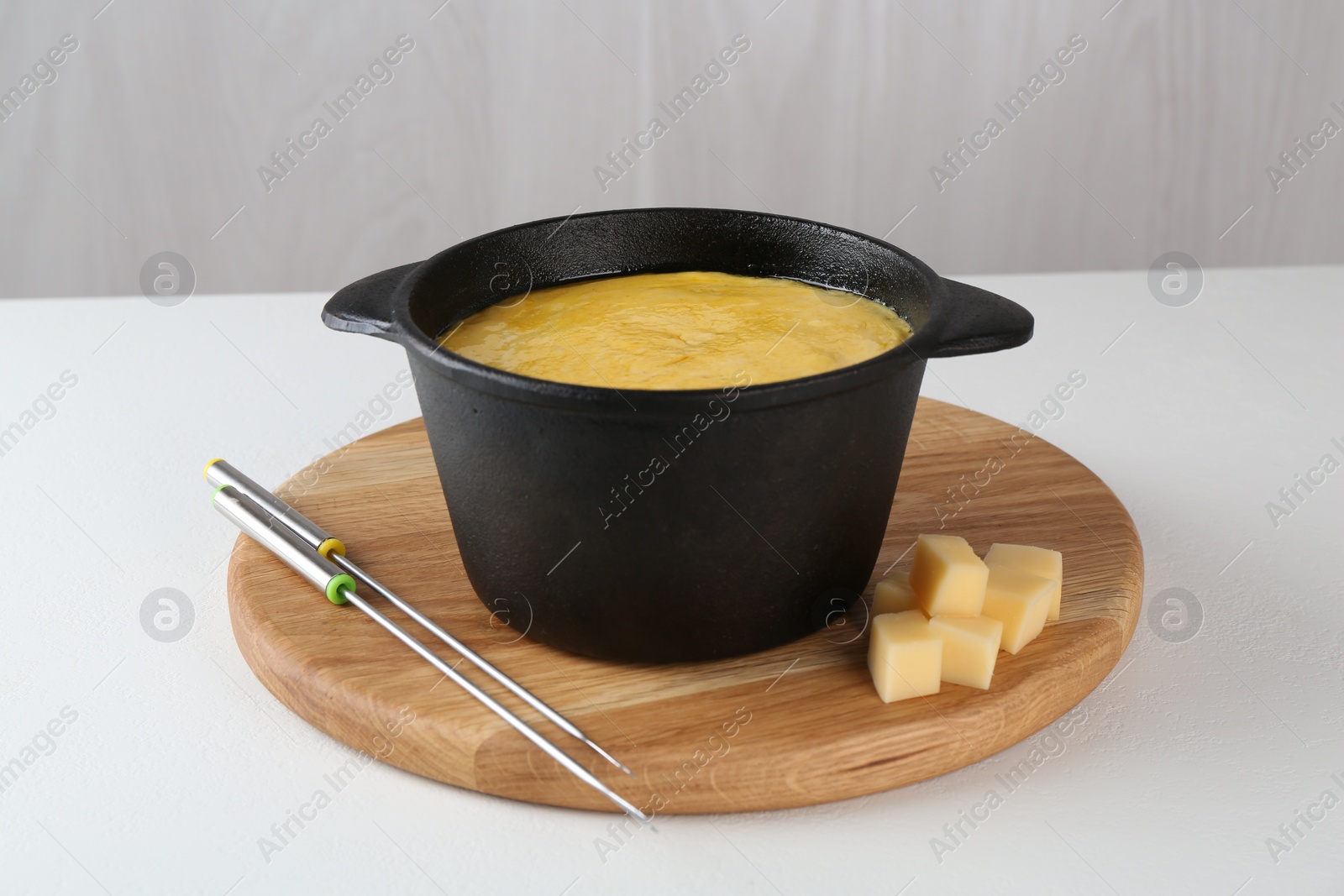 Photo of Fondue with tasty melted cheese and forks on white table