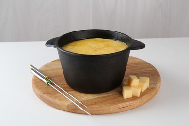 Photo of Fondue with tasty melted cheese and forks on white table