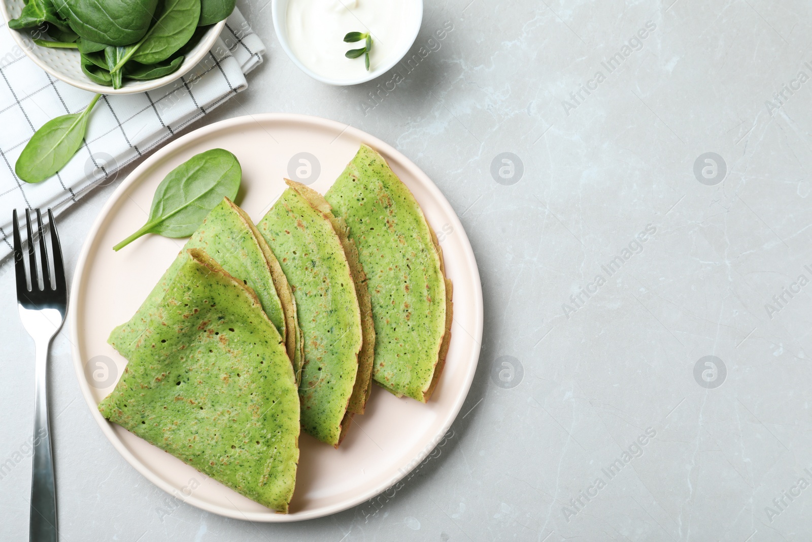 Photo of Tasty spinach crepes served on light grey marble table, flat lay. Space for text