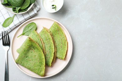 Tasty spinach crepes served on light grey marble table, flat lay. Space for text