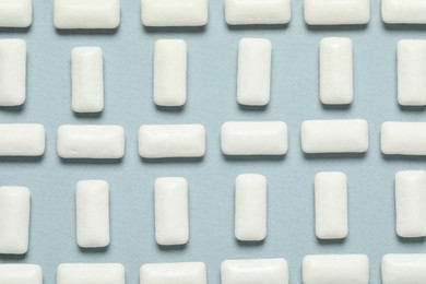 Photo of Tasty white chewing gums on light blue background, flat lay