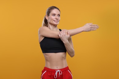 Photo of Portrait of sportswoman stretching on yellow background, space for text