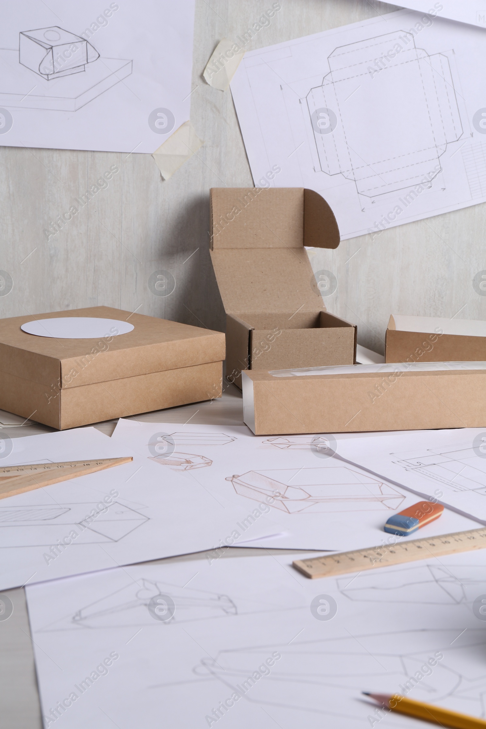 Photo of Creating packaging design. Drawings, boxes and stationery on light table, closeup